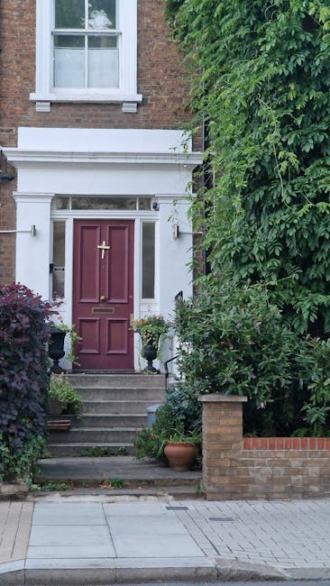 A charming terraced brick house with two green front doors numbered 31 and 33, each with a letterbox and decorative door knocker. The facade features a white-framed bay window on the left, with reflec